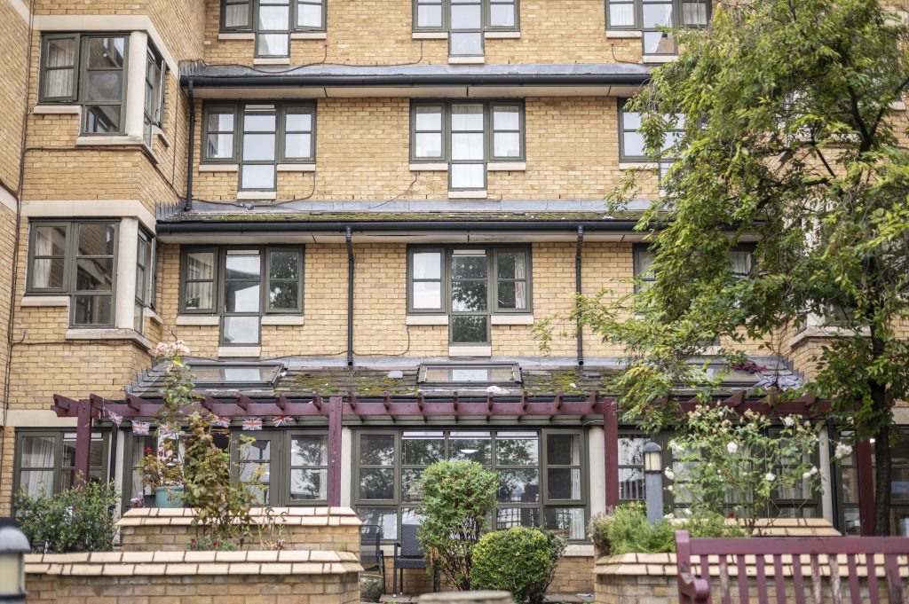 Exterior view of Alan Morkill care home featuring a brick facade, multiple windows, and landscaped gardens with greenery.