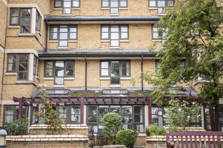 Exterior view of Alan Morkill care home featuring a brick facade, multiple windows, and landscaped gardens with greenery.
