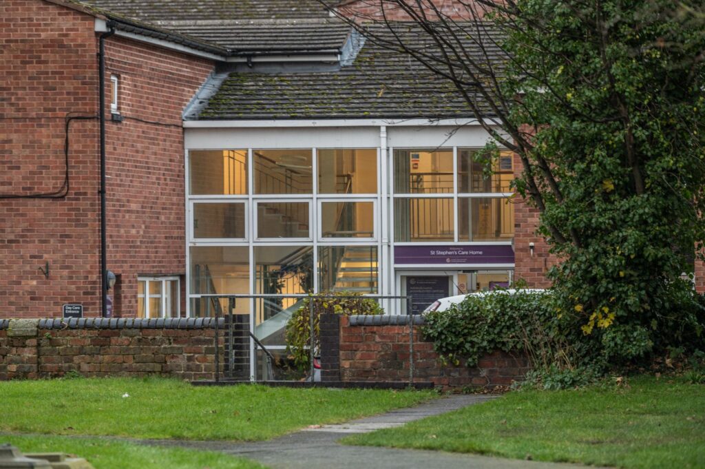 Modern brick building of St Stephen's Care Home, featuring large glass windows and a welcoming entrance surrounded by greenery.