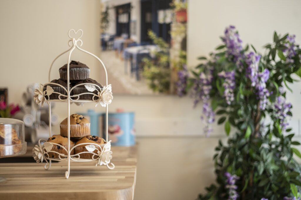 Tiered stand with chocolate and blueberry muffins in a Stevenage care home, set beside floral decor.