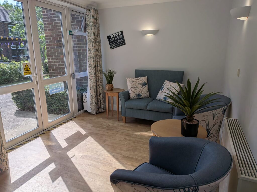 A bright lounge at Queensway House with blue seating, potted plants and glass doors.
