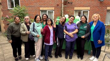 A group of smiling staff members pose together outdoors at Lansdowne Care Home during the Macmillan Coffee Morning event.