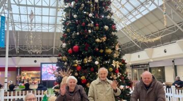 Residents of Drayton Village enjoy the festive atmosphere by a beautifully decorated Christmas tree in a shopping center.