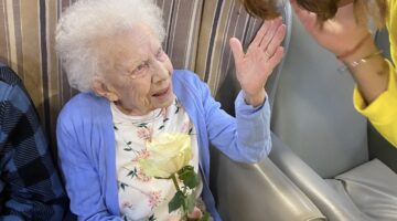 Elderly Woman in Care Home Receives Flower from Visitor