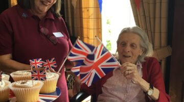 Care worker and elderly woman enjoying a UK themed party