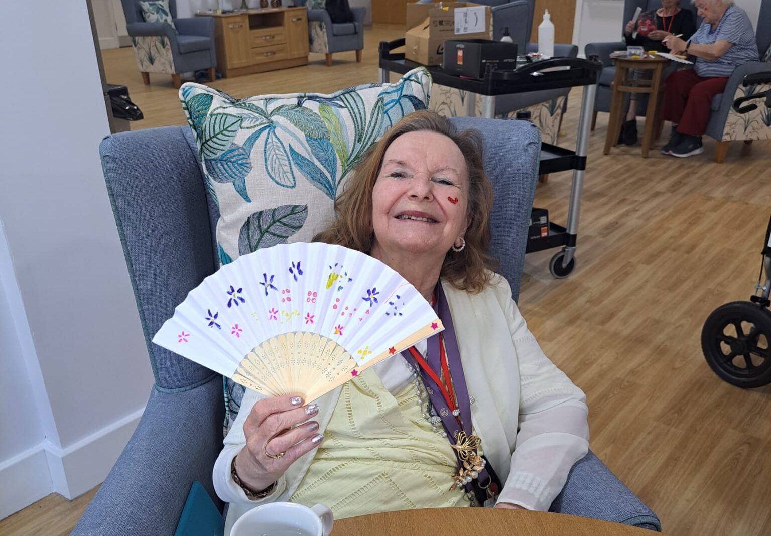 Smiling resident holding a colourful fan at Lynwood Explorer