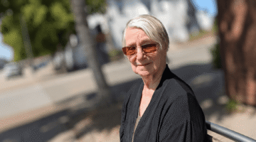 Elderly woman in sunglasses enjoying a sunny stroll in Headington