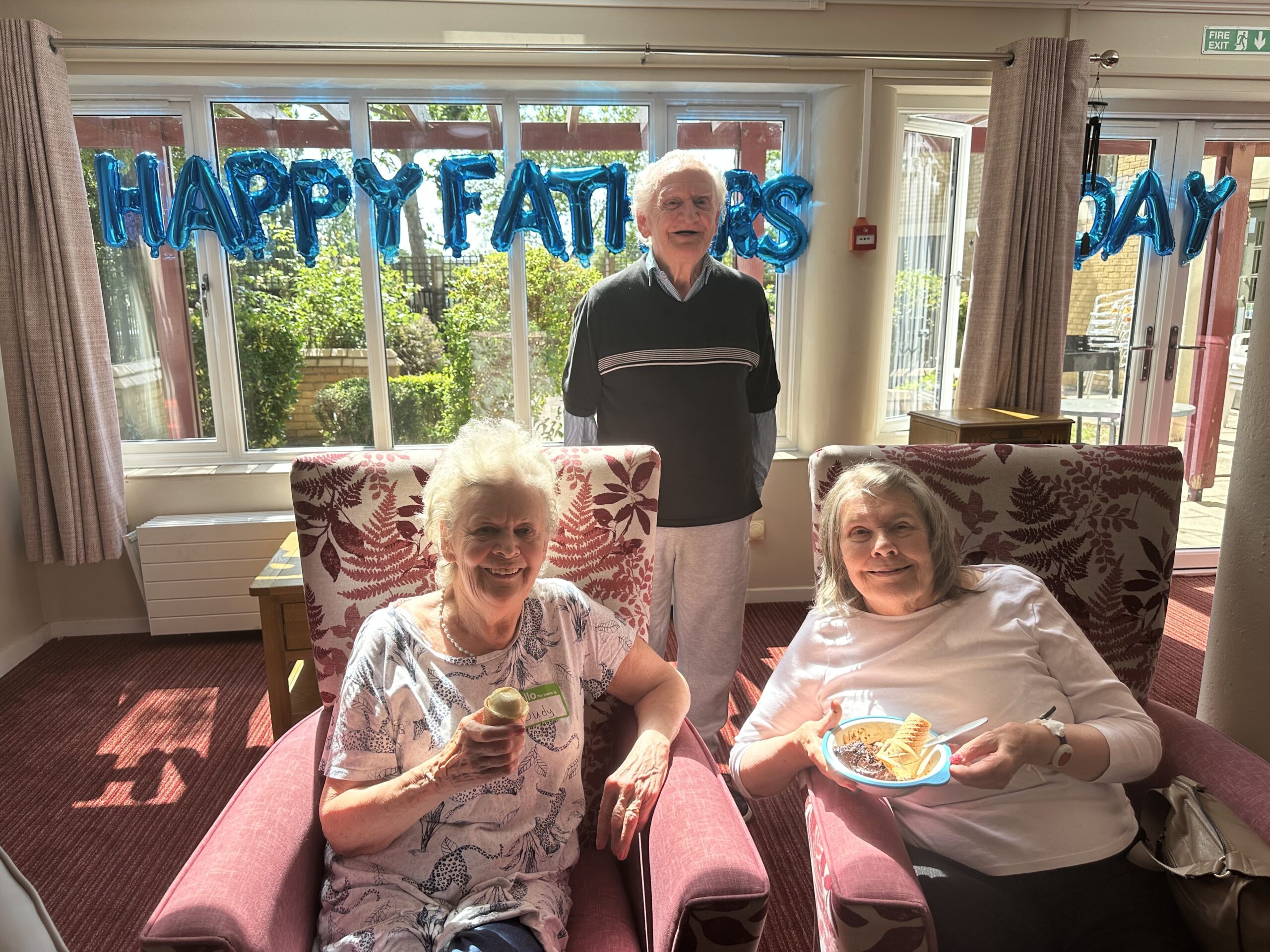 Elderly residents enjoy birthday treats with Happy Birthday balloons