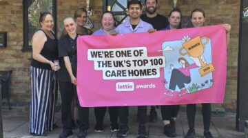Tudors Care Home team holding Lottie Awards Top 100 banner