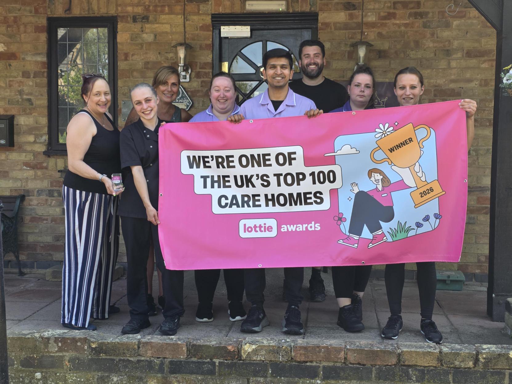 Tudors Care Home team holding Lottie Awards Top 100 banner