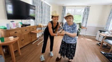 Care home activities: friendly carer and resident dancing together