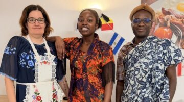 Three people in cultural outfits with South African flag