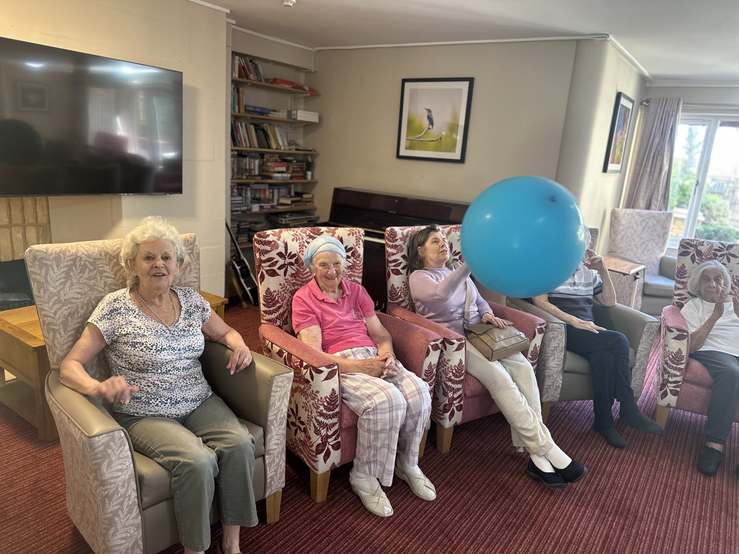 Elderly residents enjoying a care home activity with balloon