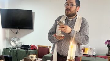 Clergy member holds communion chalice during faith service