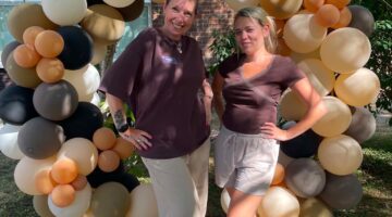 Garden balloon arch with team members at outdoor celebration