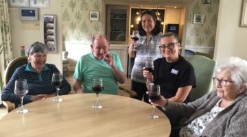 Care home residents toasting with wine during social gathering