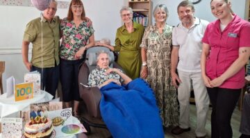 Care home birthday celebration with residents and staff holding balloons