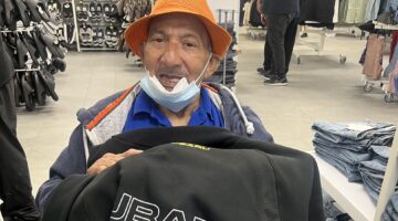 Elderly man trying on clothes in retail store, wearing mask