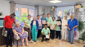 Care home staff and residents smiling with gift bags in lounge