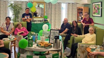 Macmillan coffee morning celebration with balloons in care home lounge