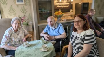 Elderly couple enjoying tea with friends at care home