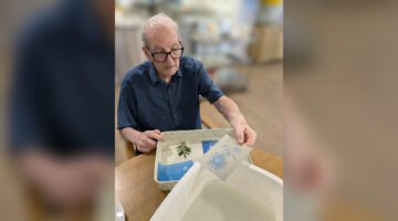 St Stephens resident holding cyanography prints for Photo Day